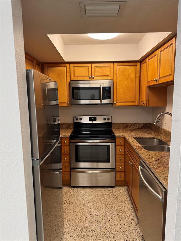 A galley kitchen features stainless steel appliances, wood cabinets, and granite countertops — 4200 1ST STREET UNIT 2, ST PETERSBURG, FL