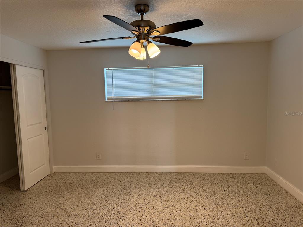 A bedroom features light gray walls, speckled flooring, a ceiling fan, and a window with blinds — 4200 1ST STREET UNIT 2, ST PETERSBURG, FL