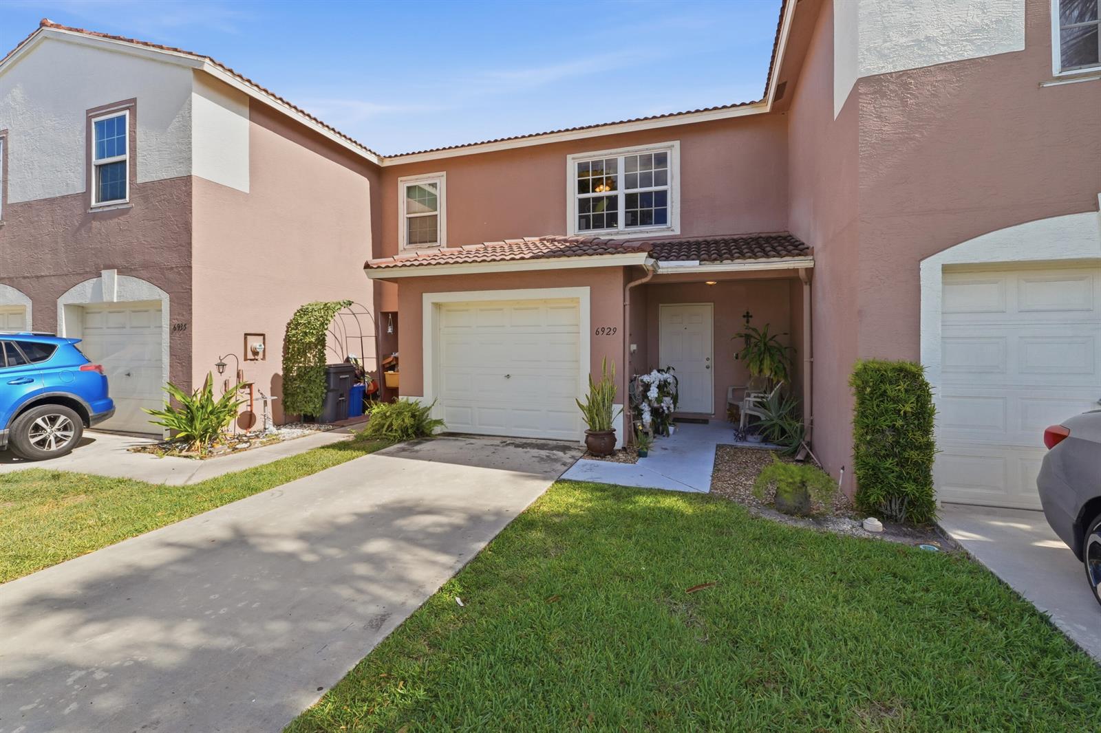 A two-story townhouse exterior features a beige stucco facade, a garage, and a front entrance — 6929 Willow Creek Run, Lake Worth FL 33463, LAKE WORTH, FL