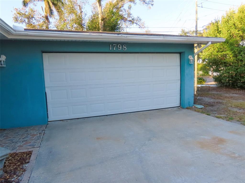 A white garage door is centered on the blue exterior wall of a house — 1798 FAULDS ROAD N, CLEARWATER, FL