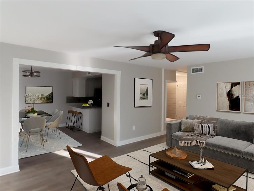 A living room with a ceiling fan, gray sofa, and coffee table opens to a dining area — 1798 FAULDS ROAD N, CLEARWATER, FL