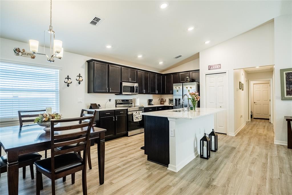 A kitchen with dark cabinets, a white island, and an adjacent dining area — 3307 COSTELLO CIRCLE, WINTER HAVEN, FL