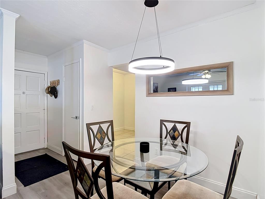 A dining area features a glass-topped table, four chairs, a modern pendant light, and mirror — 4611 W NORTH B STREET UNIT 240, TAMPA, FL