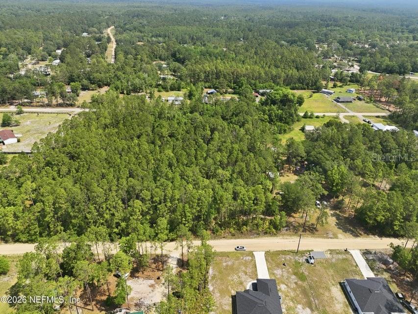 An aerial view shows a large, wooded lot bordered by a dirt road and houses — 490 KAY ROAD, MIDDLEBURG, FL