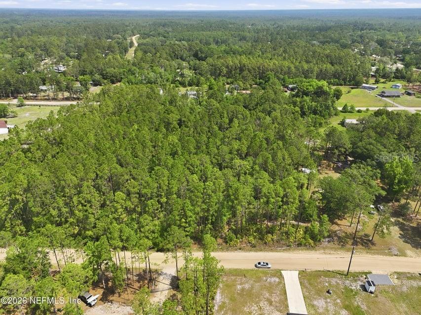 An aerial view shows a wooded lot bordered by a dirt road and neighboring houses — 490 KAY ROAD, MIDDLEBURG, FL
