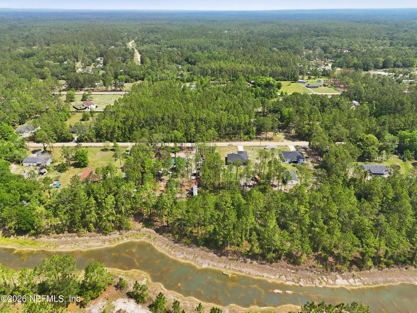 An aerial view shows a rural residential area with scattered houses, dense trees, and a pond — 490 KAY ROAD, MIDDLEBURG, FL