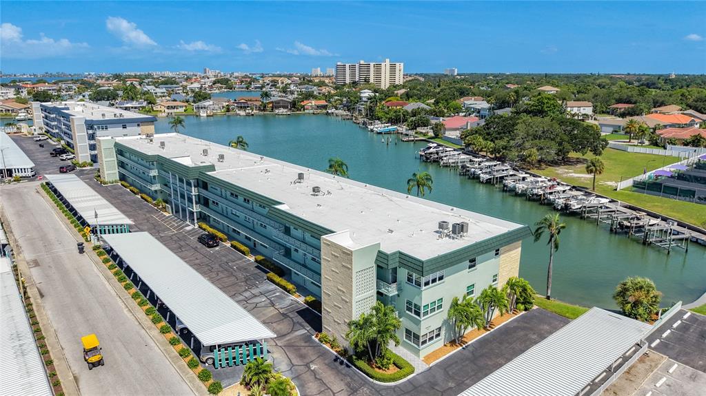 An aerial view shows a multi-story apartment building with a parking lot and boat docks — 5935 30TH AVENUE S UNIT 104, GULFPORT, FL