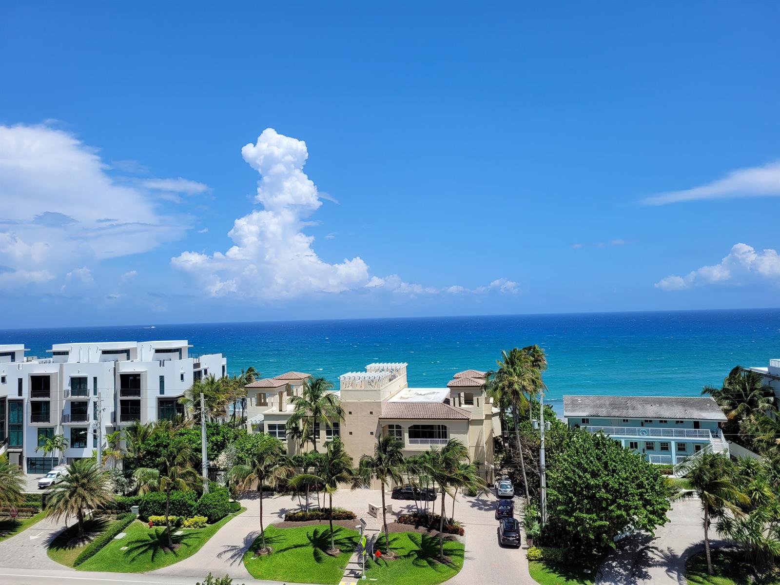 An elevated view of coastal buildings, palm trees, and a blue ocean under a sunny sky — 3700 S Ocean Boulevard # 705, Highland Beach FL 33487, HIGHLAND BEACH, FL