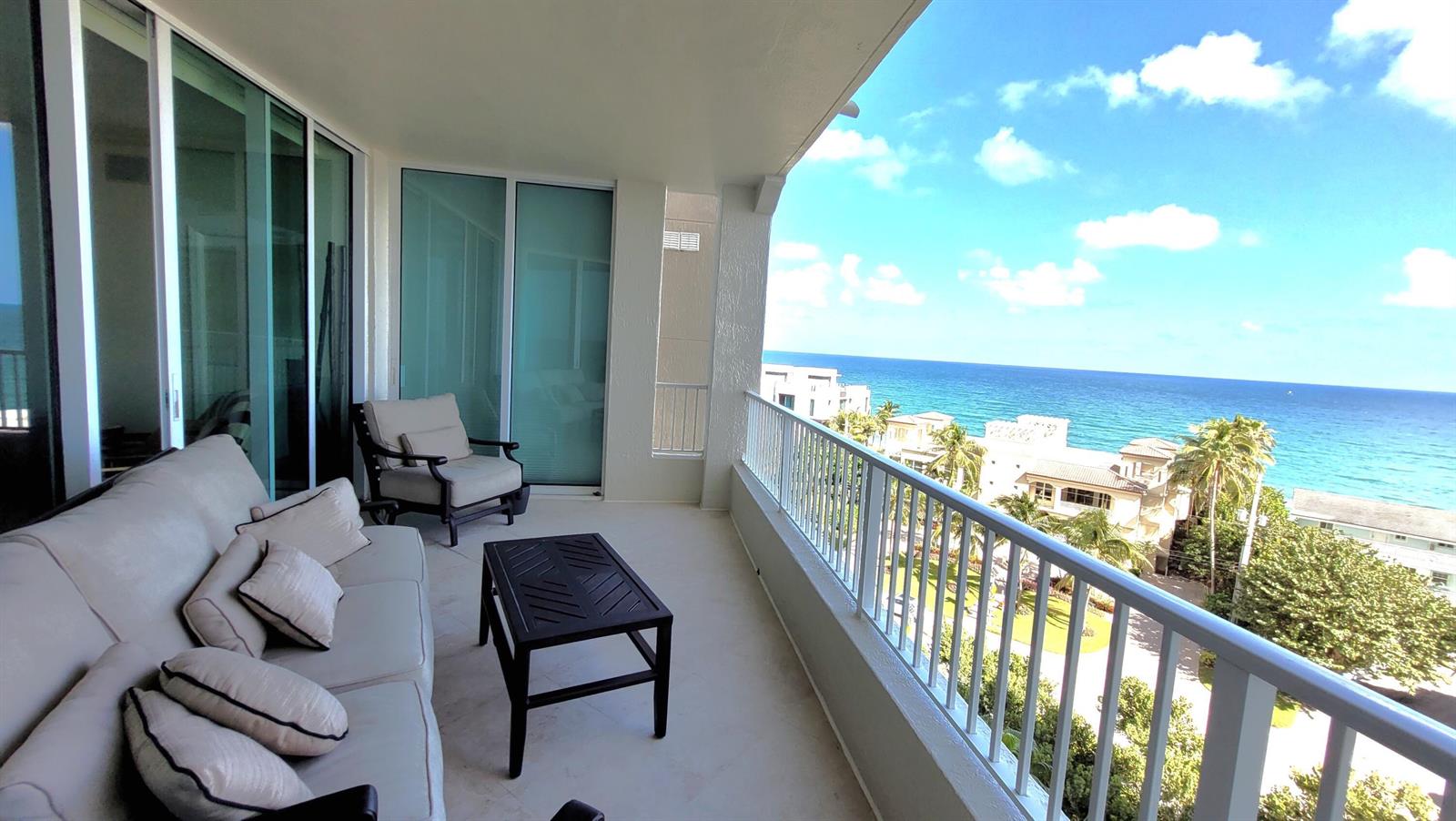 A balcony with outdoor seating overlooks the ocean and nearby coastal buildings — 3700 S Ocean Boulevard # 705, Highland Beach FL 33487, HIGHLAND BEACH, FL
