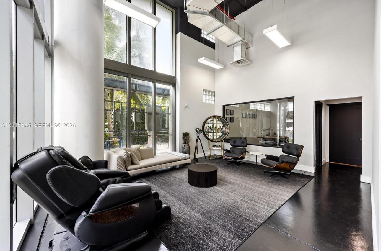 A modern, high-ceilinged lounge features a large rug, leather chairs, and floor-to-ceiling windows — 92 SW 3rd St, Miami FL 33130, MIAMI, FL