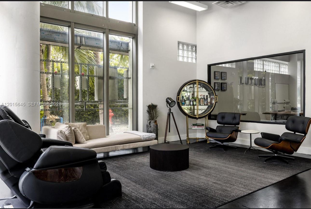 A modern lounge area features floor-to-ceiling windows, a dark rug, and mid-century modern furniture — 92 SW 3rd St, Miami FL 33130, MIAMI, FL