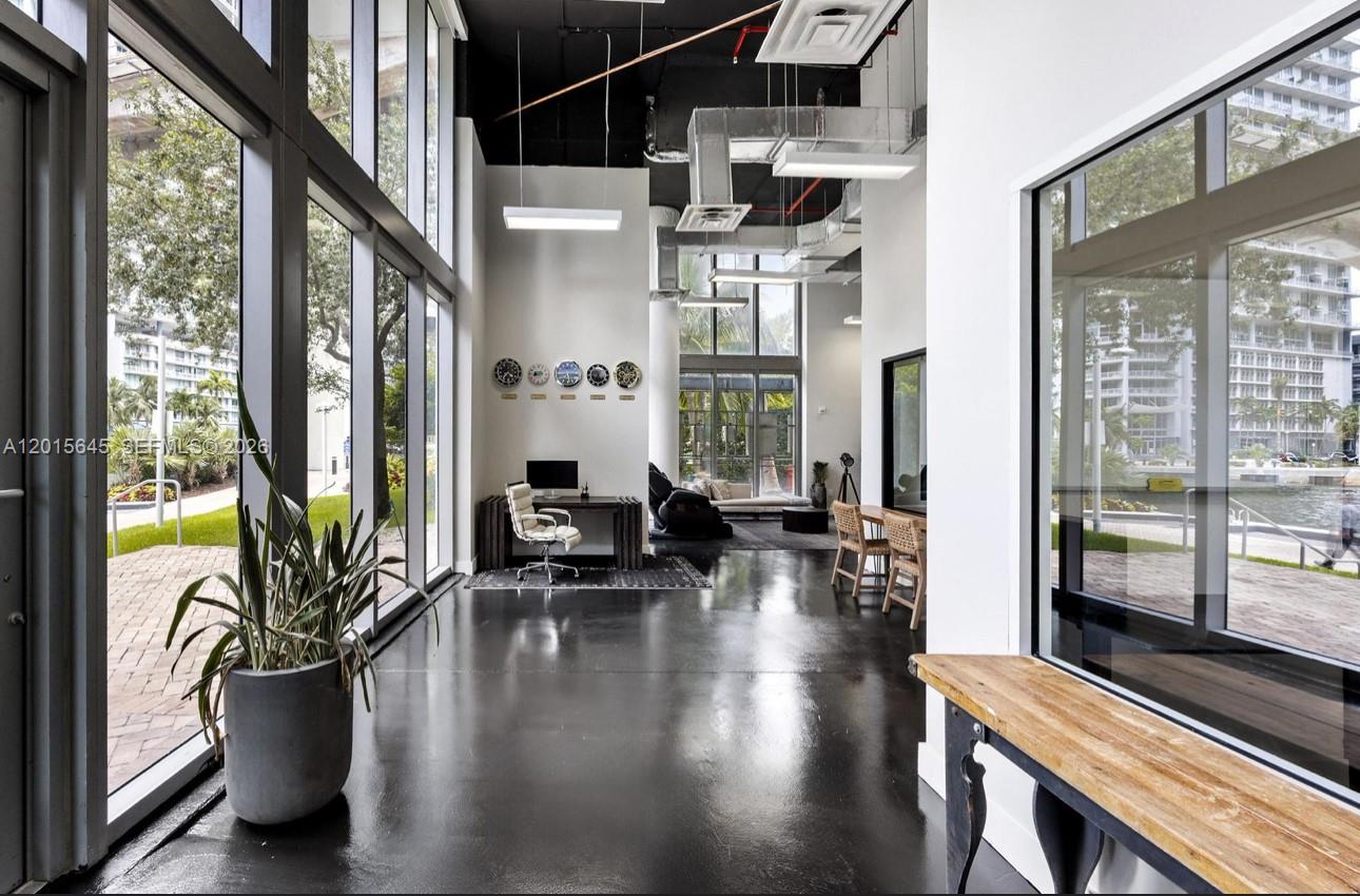 A modern office space features high ceilings, black floors, floor-to-ceiling windows, and a desk area — 92 SW 3rd St, Miami FL 33130, MIAMI, FL