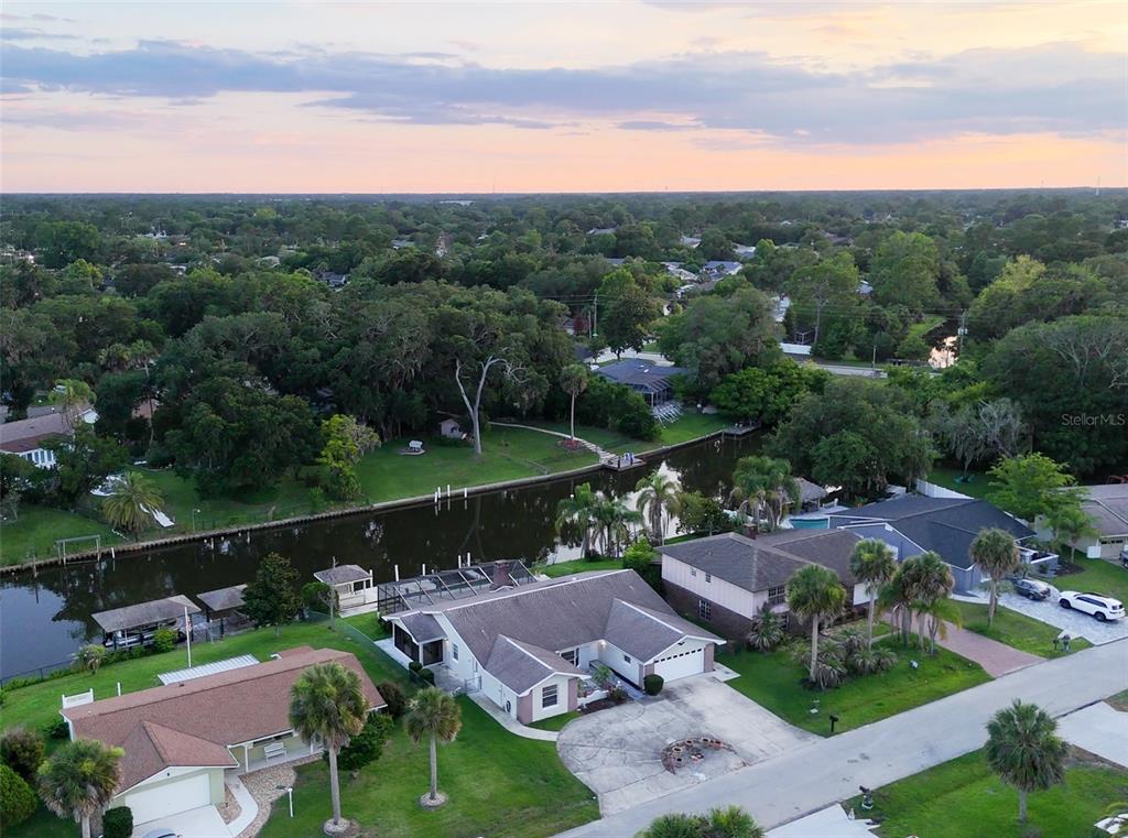 An aerial view shows a suburban neighborhood with houses along a canal at sunset — 10 FELICIA COURT, PALM COAST, FL