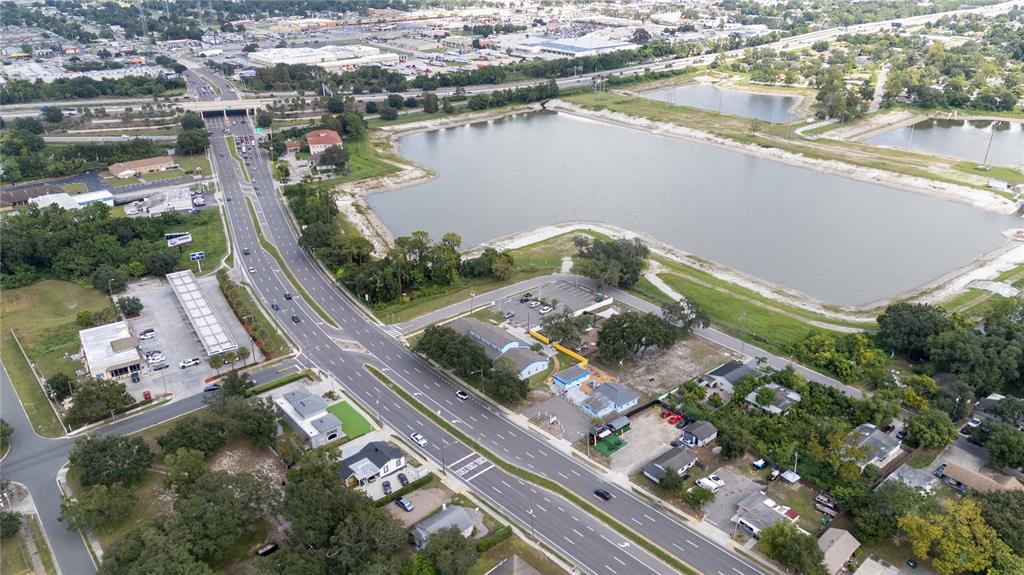 An aerial view shows a multi-lane road, a large retention pond, and surrounding commercial properties — 217 N KIRKMAN ROAD, ORLANDO, FL