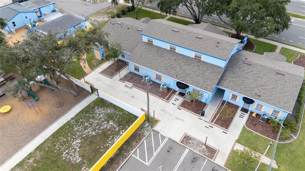 An aerial view shows a light blue commercial building with a gray roof and playground — 217 N KIRKMAN ROAD, ORLANDO, FL