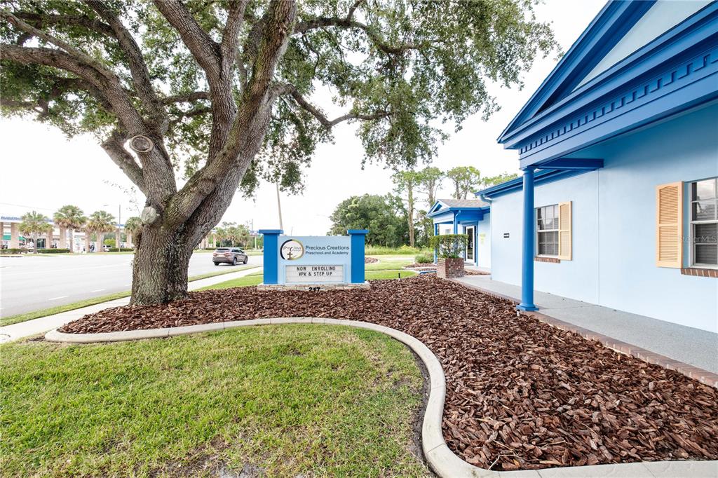 A blue building with a sign for a preschool sits behind a large oak tree — 217 N KIRKMAN ROAD, ORLANDO, FL