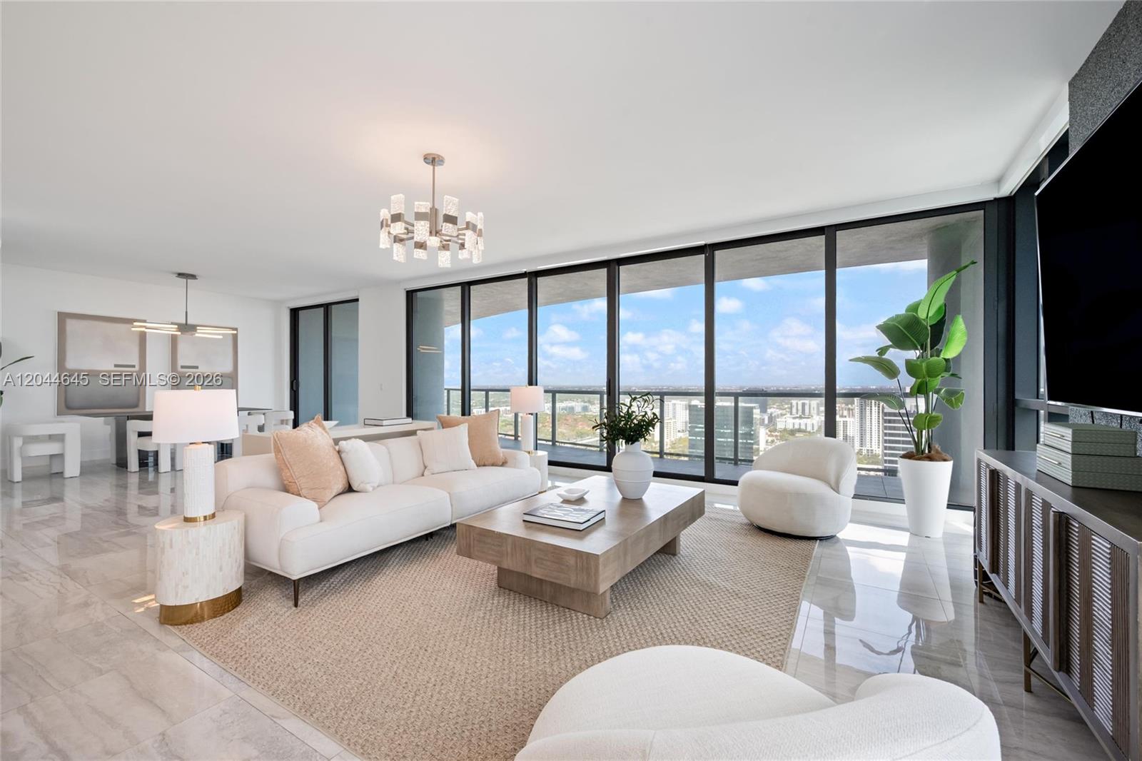 A modern living room features a white sofa, a wooden coffee table, and floor-to-ceiling windows — 100 E Las Olas Blvd # 3201, Fort Lauderdale FL 33301, FORT LAUDERDALE, FL