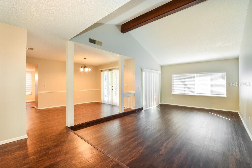 A living room with vaulted ceilings, dark wood flooring, and an adjacent dining area — 1400 PONCE DE LEON BOULEVARD, WINTER SPRINGS, FL