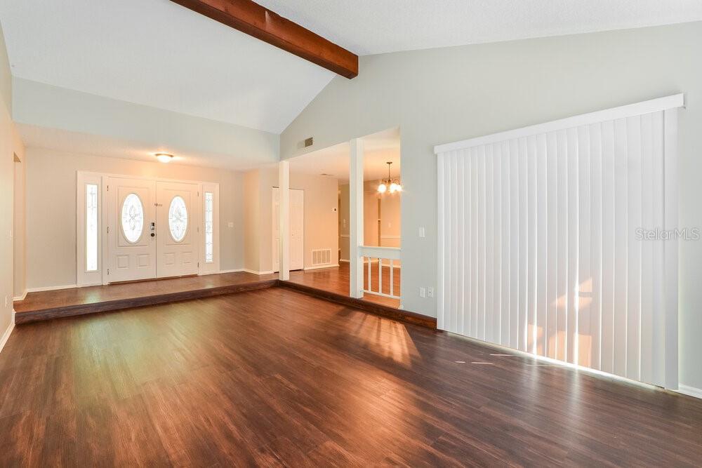 A living room with wood-look flooring, a vaulted ceiling, and a double front door — 1400 PONCE DE LEON BOULEVARD, WINTER SPRINGS, FL