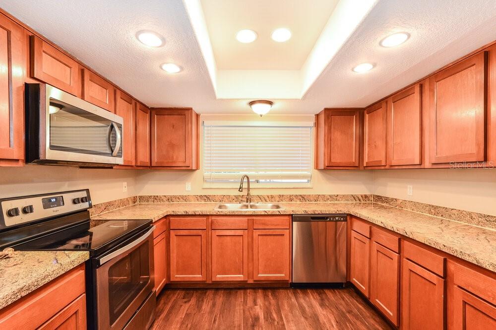 A kitchen with wood cabinets, granite countertops, stainless steel appliances, and a recessed ceiling light — 1400 PONCE DE LEON BOULEVARD, WINTER SPRINGS, FL