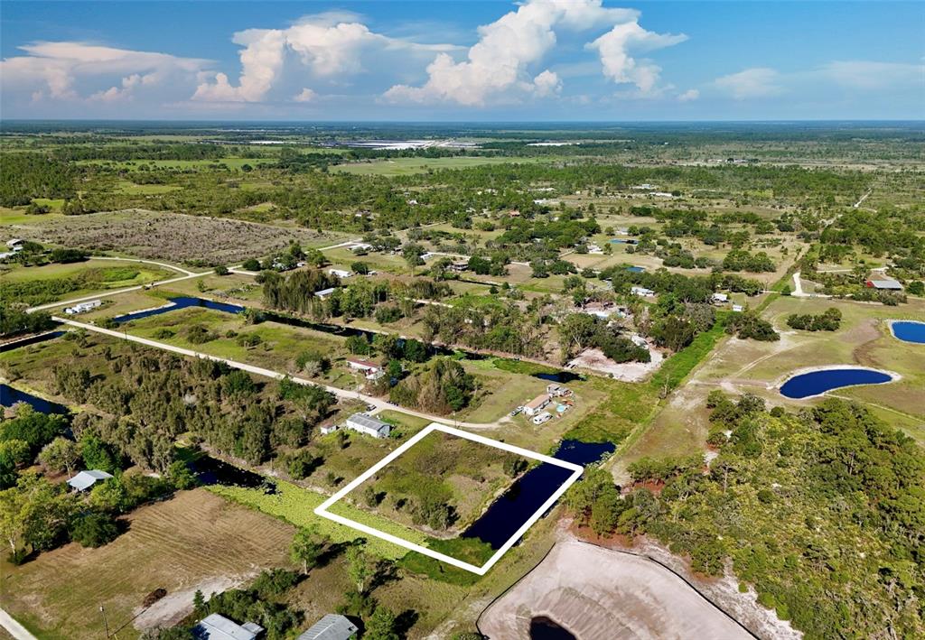 An aerial view shows a vacant, rectangular plot of land outlined in white near water — 25 CONE DRIVE, VENUS, FL
