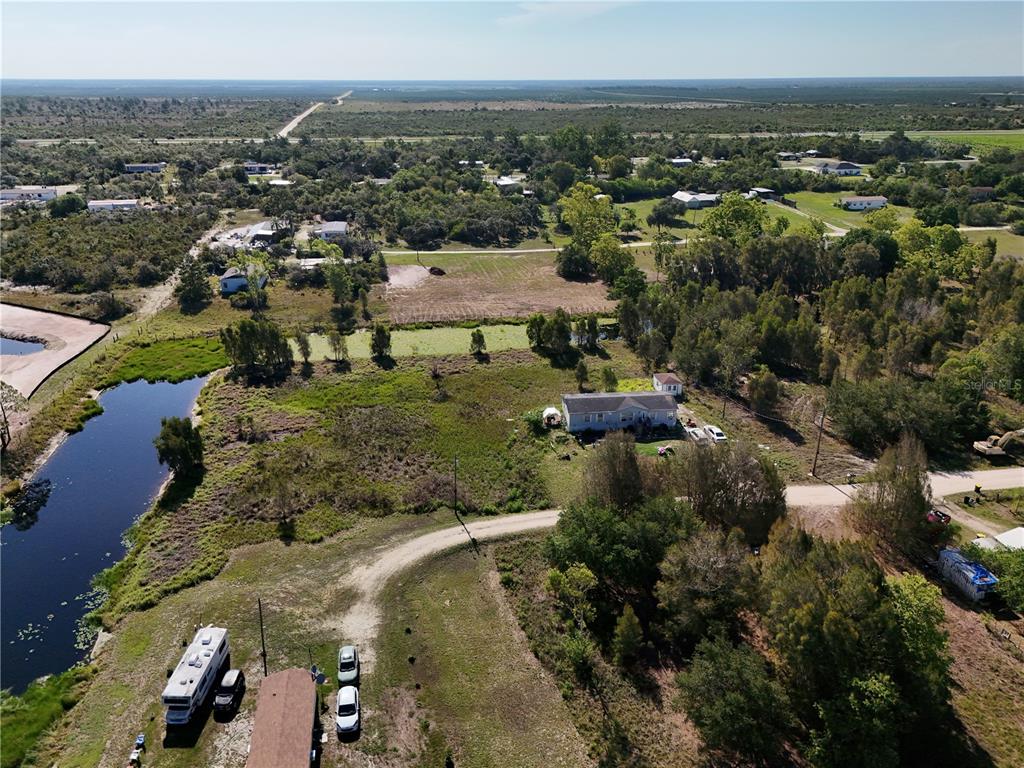 An aerial view shows a rural property with a house, a pond, and a camper — 25 CONE DRIVE, VENUS, FL