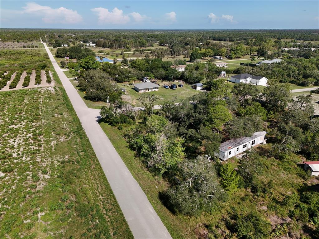 An aerial view shows a rural property with a long driveway and several detached buildings — 25 CONE DRIVE, VENUS, FL