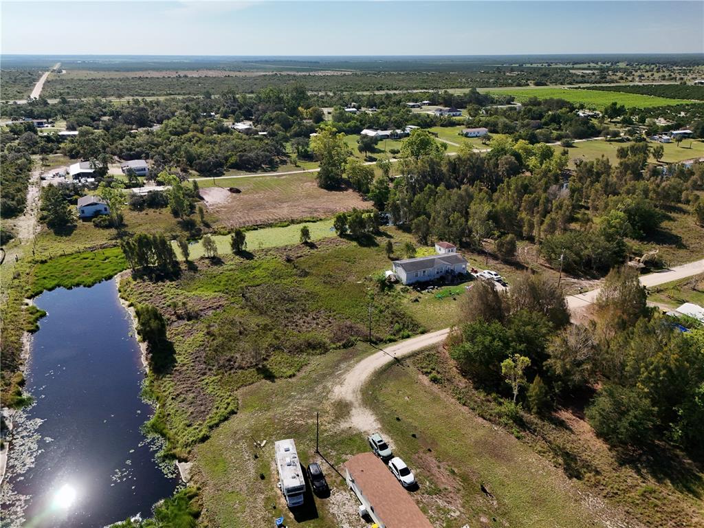 An aerial view shows a rural property with a house, a pond, and vehicles — 25 CONE DRIVE, VENUS, FL
