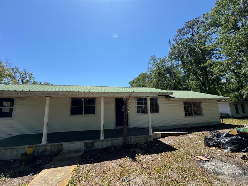A single-story house with light siding, a green metal roof, and a covered front porch — 15130 N 104TH STREET, LIVE OAK, FL