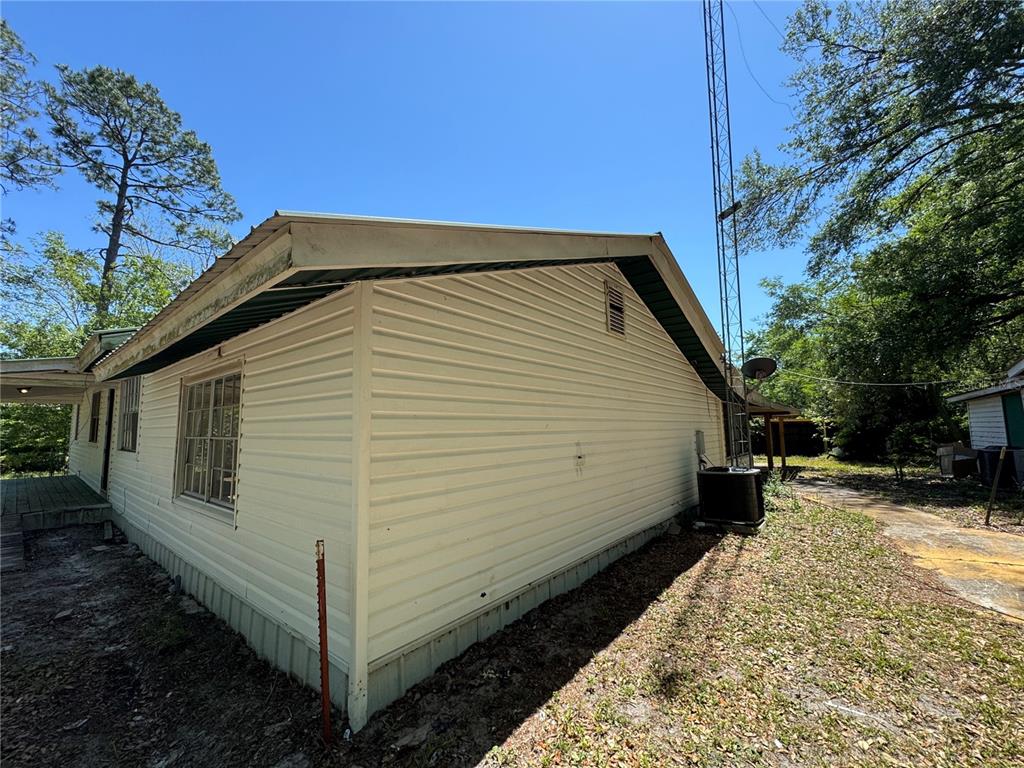 The exterior of a light-colored, single-story house features vinyl siding, a metal roof, and a tower — 15130 N 104TH STREET, LIVE OAK, FL