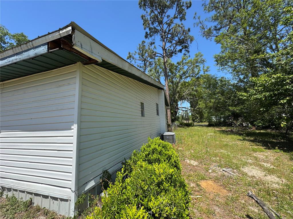 The exterior side of a white-sided mobile home features a metal roof and small windows — 15130 N 104TH STREET, LIVE OAK, FL