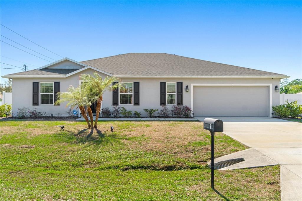 A single-story house with a beige exterior, dark shutters, a two-car garage, and a palm tree — 1 FRENORA LANE, PALM COAST, FL