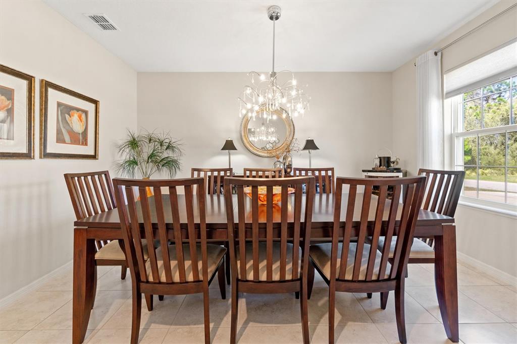 A dining room features a dark wood table, six chairs, a chandelier, and a round mirror — 1 FRENORA LANE, PALM COAST, FL