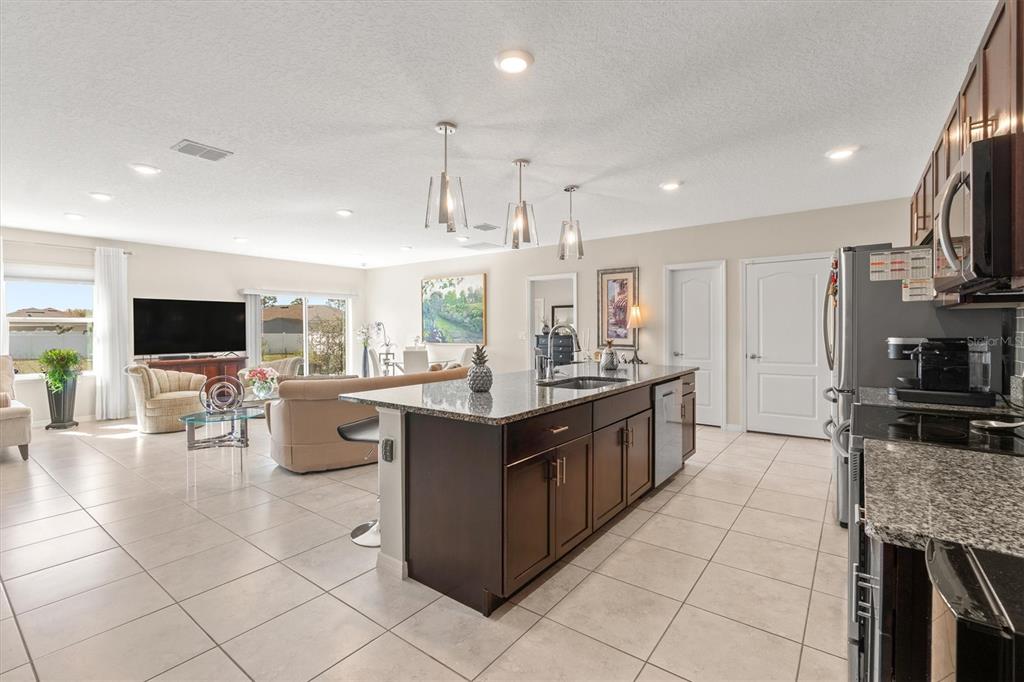 A kitchen with dark wood cabinets and granite countertops opens into a living room area — 1 FRENORA LANE, PALM COAST, FL