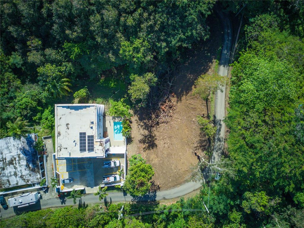 An aerial view shows a house with a pool next to a cleared, undeveloped lot — CARR. 115, KM 5.5 INT., RINCON, PR
