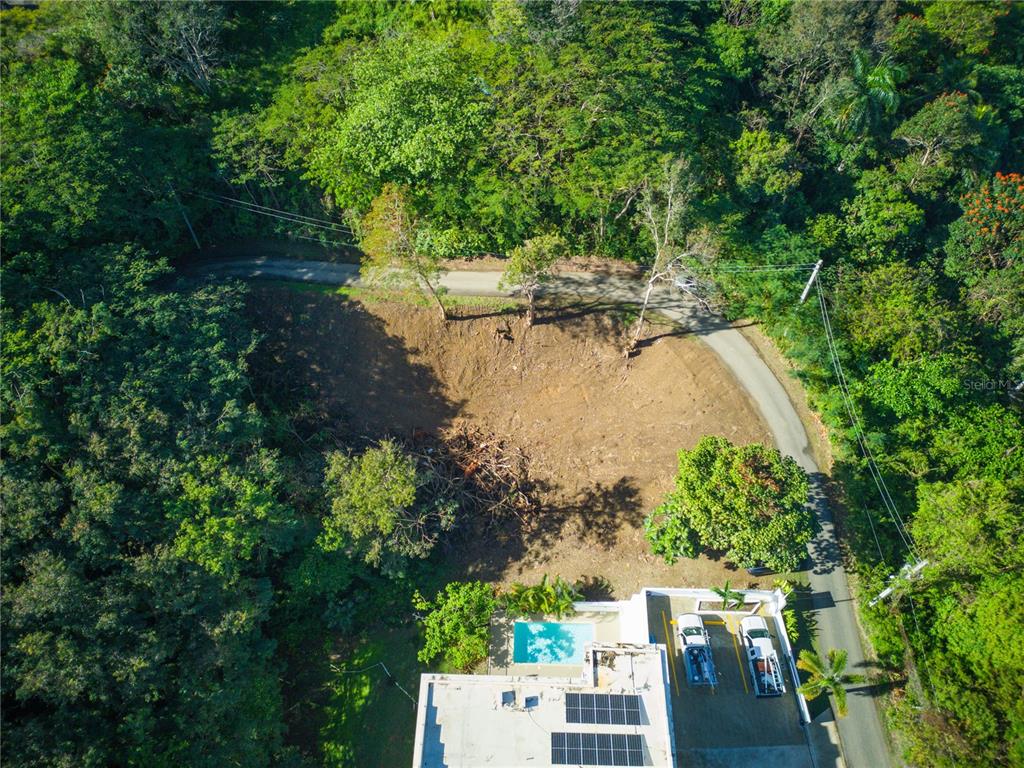 An aerial view shows a cleared dirt lot next to a house with a pool — CARR. 115, KM 5.5 INT., RINCON, PR