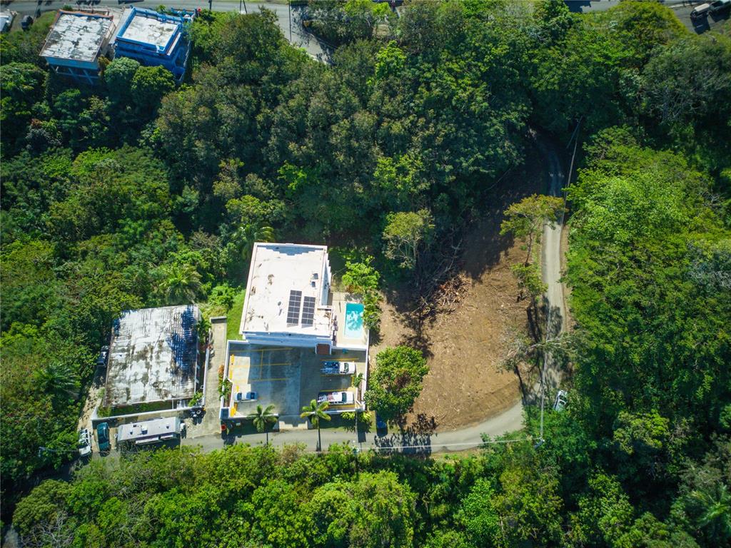 An aerial view shows a white building with a pool next to a cleared lot — CARR. 115, KM 5.5 INT., RINCON, PR