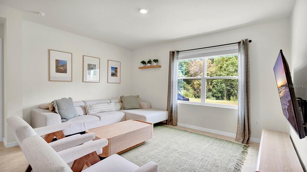 A living room features a sectional sofa, two armchairs, a coffee table, and a wall-mounted television — 3629 BOTANICAL WAY, SANFORD, FL