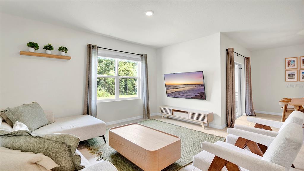 A living room features a light-colored sofa, two armchairs, a wooden coffee table, and a television — 3629 BOTANICAL WAY, SANFORD, FL