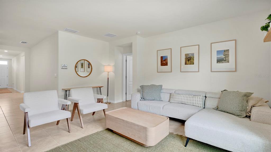 A living room features a light gray sectional sofa, two white chairs, and a coffee table — 3629 BOTANICAL WAY, SANFORD, FL