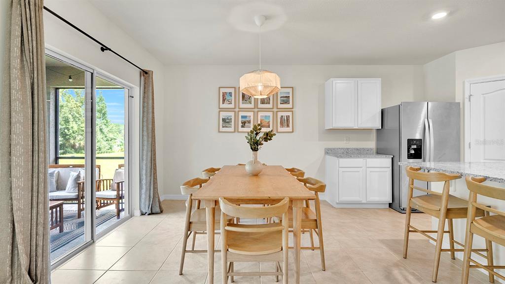 A dining area with a wooden table, chairs, and a sliding door to a patio — 3629 BOTANICAL WAY, SANFORD, FL