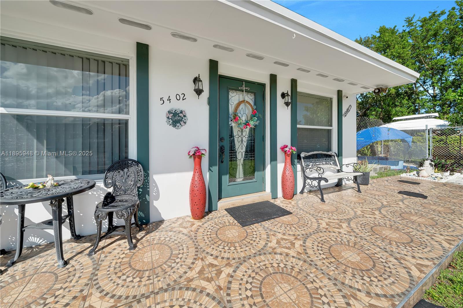 A front patio features patterned tile flooring, a metal table and chairs, and a green door — 5402 SW 128th Pl, Miami FL 33175, MIAMI, FL