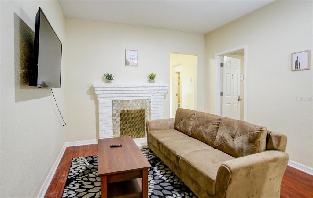 A living room features a brown sofa, a white brick fireplace, and a wall-mounted television — 1219 E EMMA STREET, TAMPA, FL