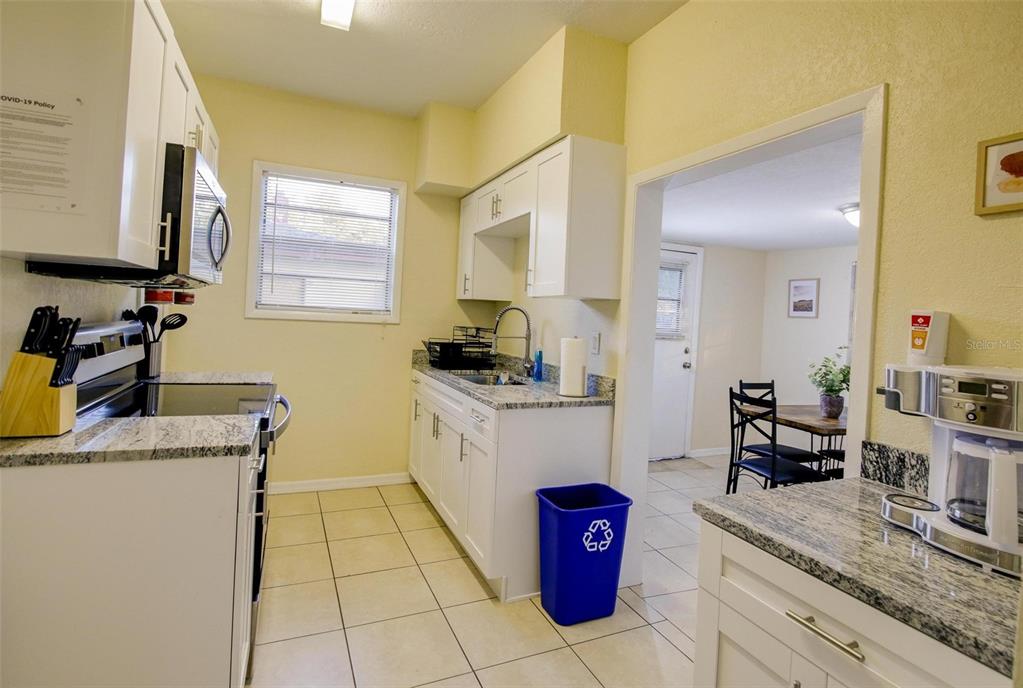A kitchen features white cabinets, granite countertops, tile flooring, and an adjacent dining area — 1219 E EMMA STREET, TAMPA, FL