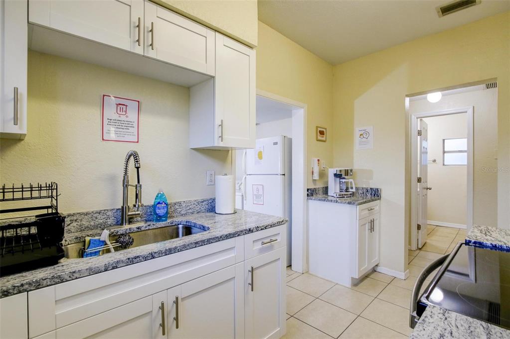 A kitchen features white cabinets, granite countertops, a stainless steel sink, and a white refrigerator — 1219 E EMMA STREET, TAMPA, FL