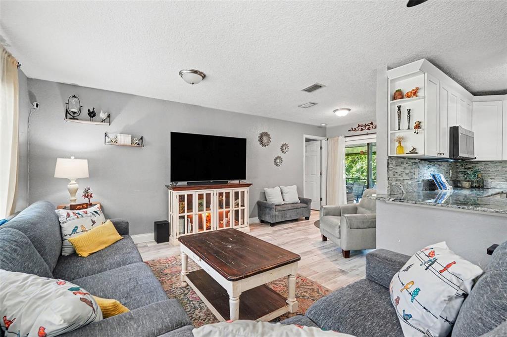 A living room with gray sofas, a wooden coffee table, and an open kitchen area — 534 LEVERETT ROAD, SEFFNER, FL
