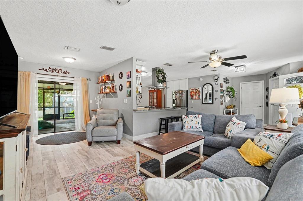 A living room with gray walls, wood-look flooring, a gray sectional sofa, and an open kitchen — 534 LEVERETT ROAD, SEFFNER, FL