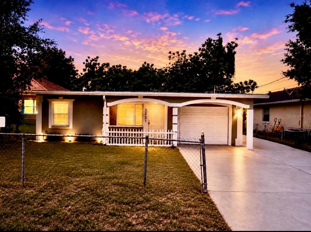 A single-story house with a white picket fence, a garage, and a concrete driveway at sunset — 300 S BUENA VISTA AVENUE, ORLANDO, FL