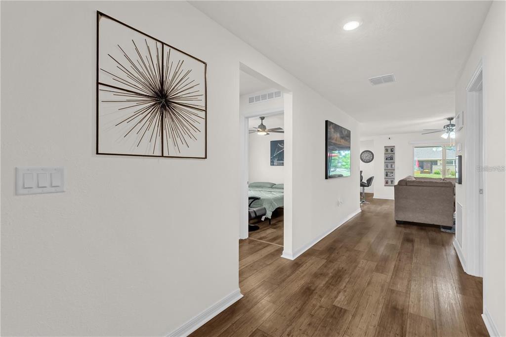 A hallway with wood-look flooring leads to a living room and a bedroom — 1898 9TH AVENUE, DELAND, FL