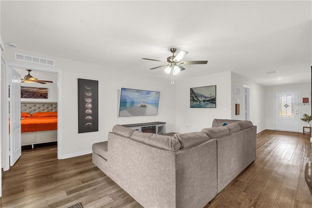 A living room with a gray sectional sofa, a wall-mounted television, and wood-look flooring — 1898 9TH AVENUE, DELAND, FL